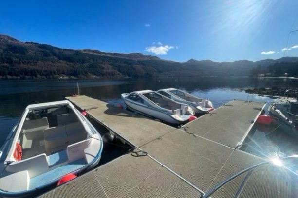 Upside-down view of boats docked on a calm lake with a mountainous backdrop.