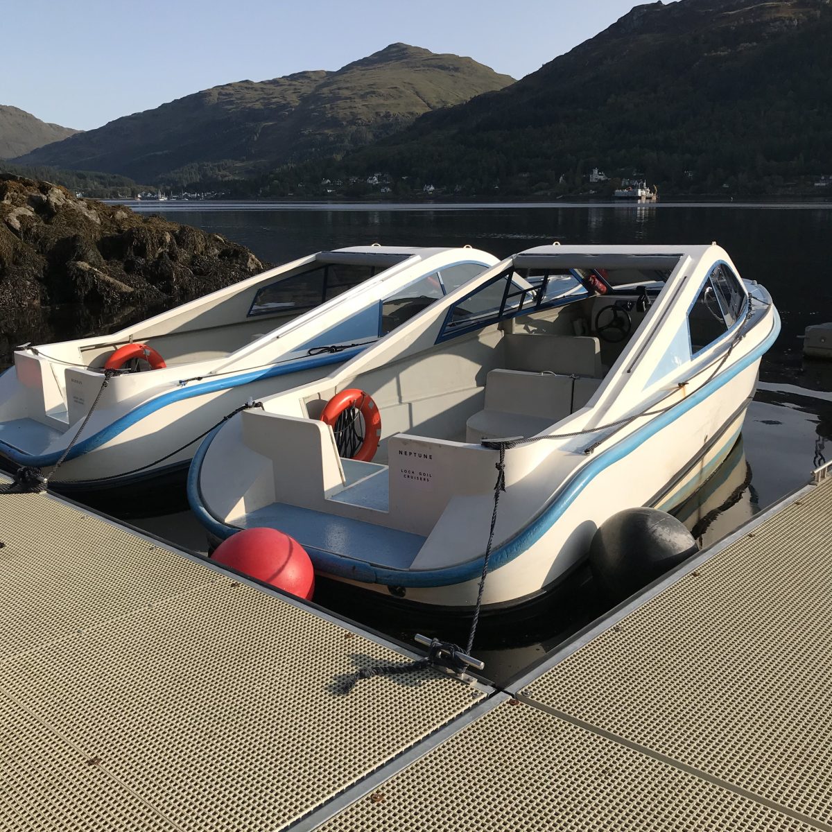 Speedboat docked by a mountain lake on a sunny day.
