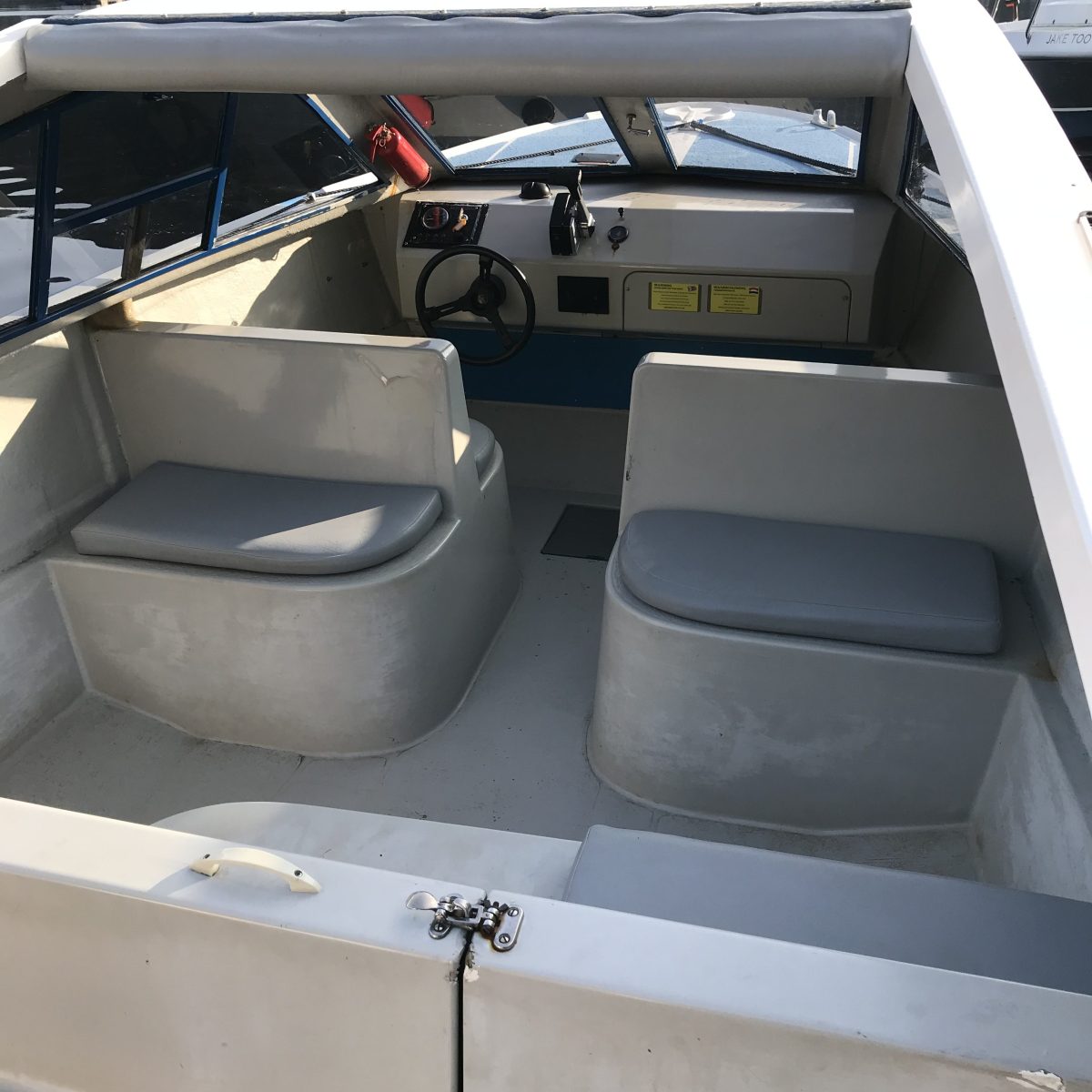 Interior of a boat showing seating and steering wheel.