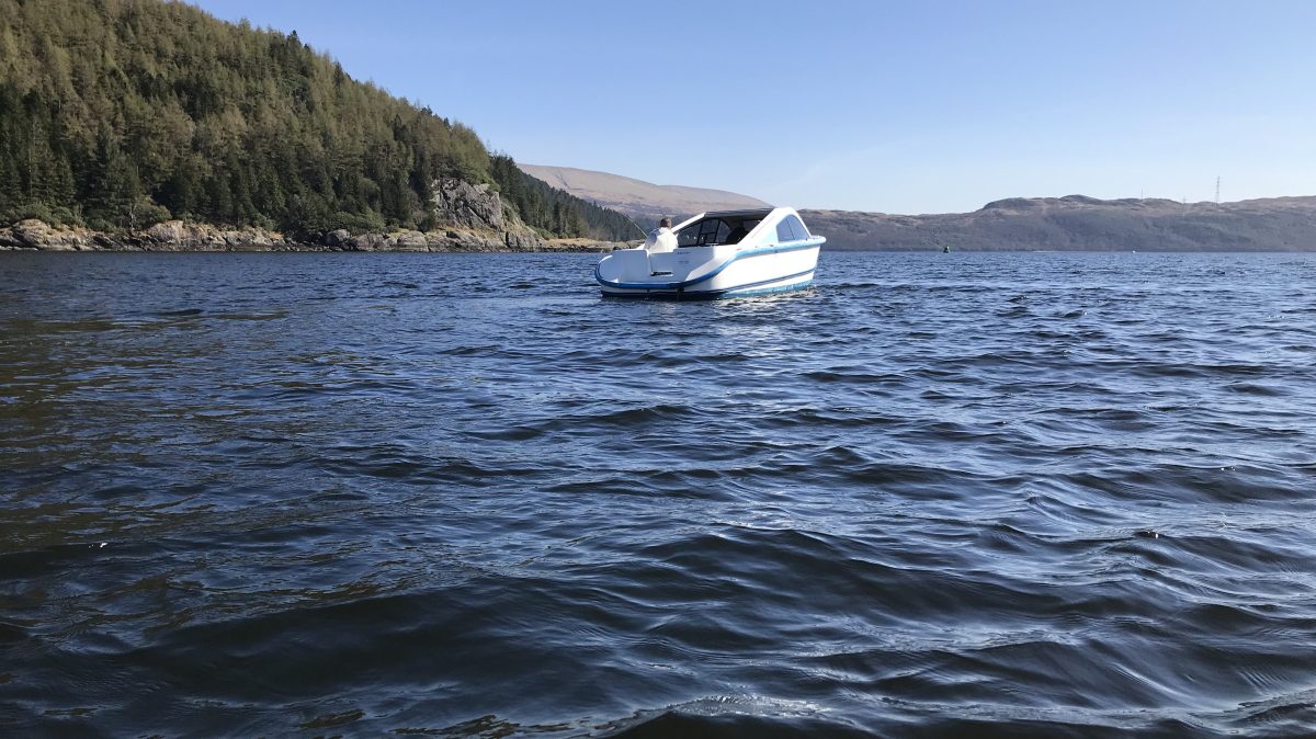 Upside-down image of a small boat on a calm lake near a forested shore.
